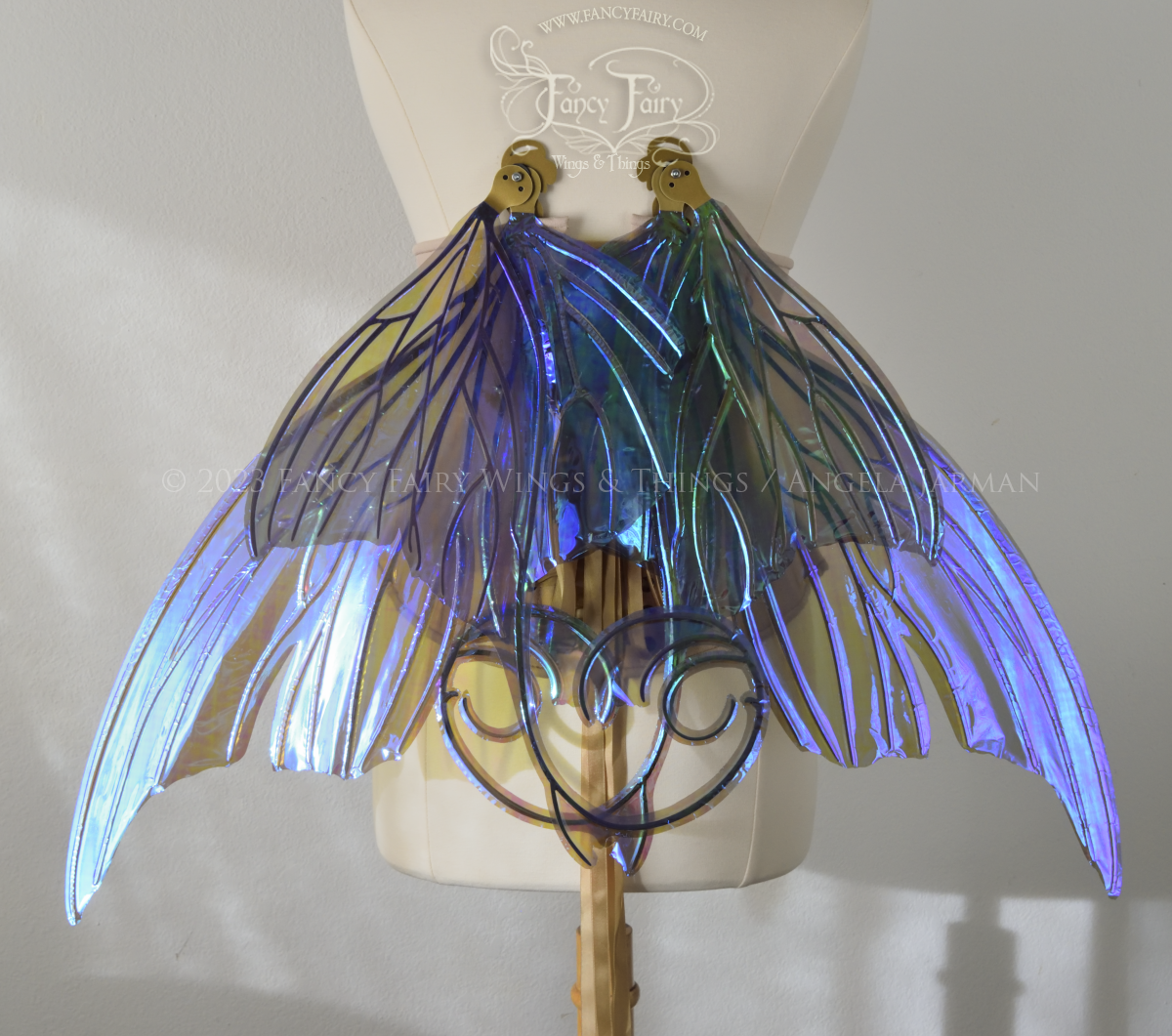 Back view of an ivory dress form wearing an alabaster underbust corset and large purple iridescent fairy wings with lots of intricate gold veins, some have 'thorns'. Upper panels curve slightly downwards along top edge with pointy tips, bottom panels have tails. In resting position