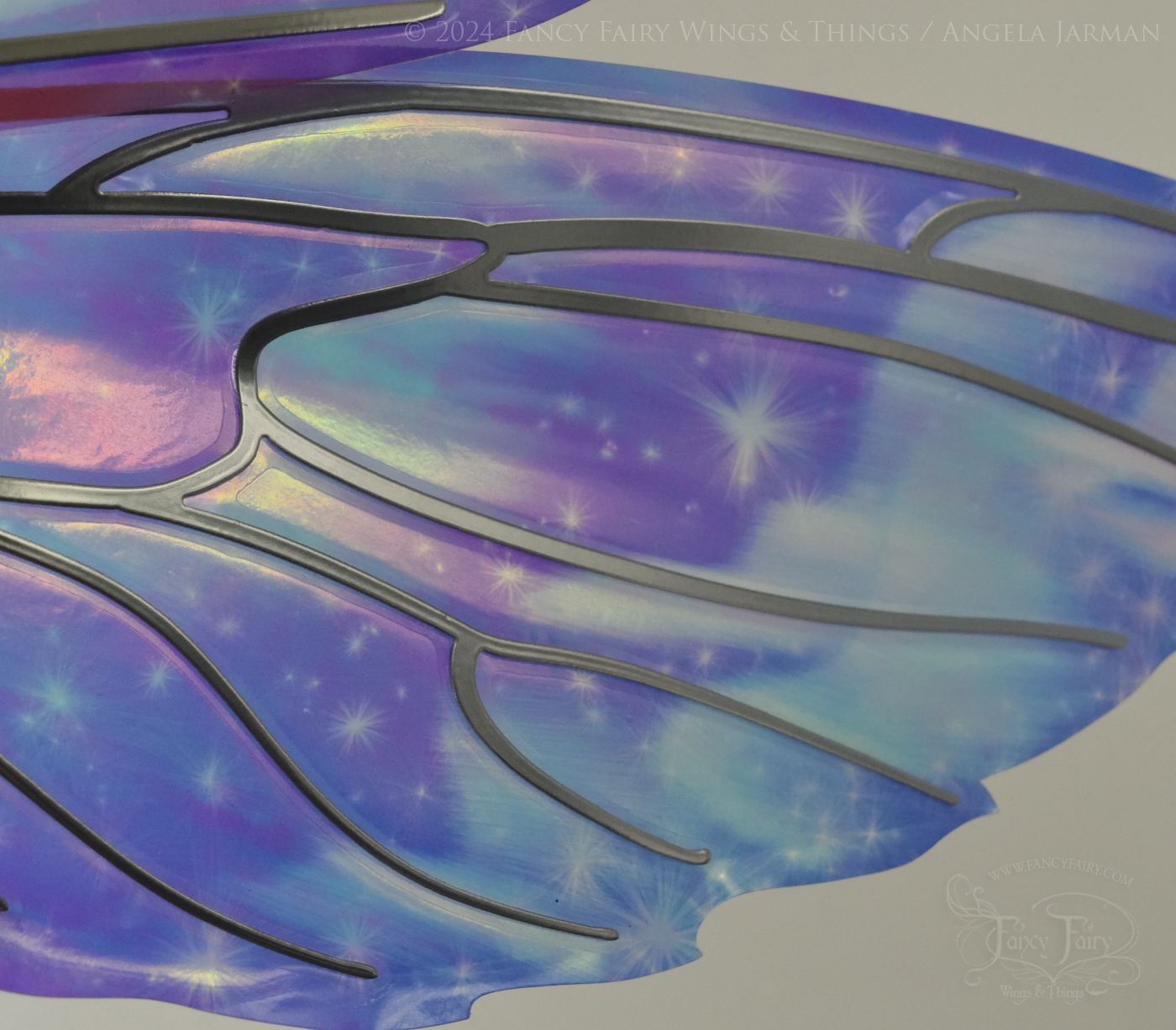 Close-up of bottom right panel of iridescent fairy wings with pointed tips & antennae, painted with auroras & stars in pinks, purples & blues, with silver veins