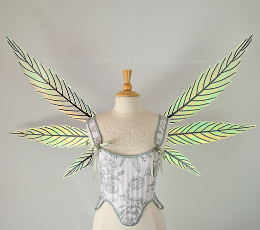 Green iridescent fairy wings styled after hemp leaves with black veins, worn on a dress form, front view