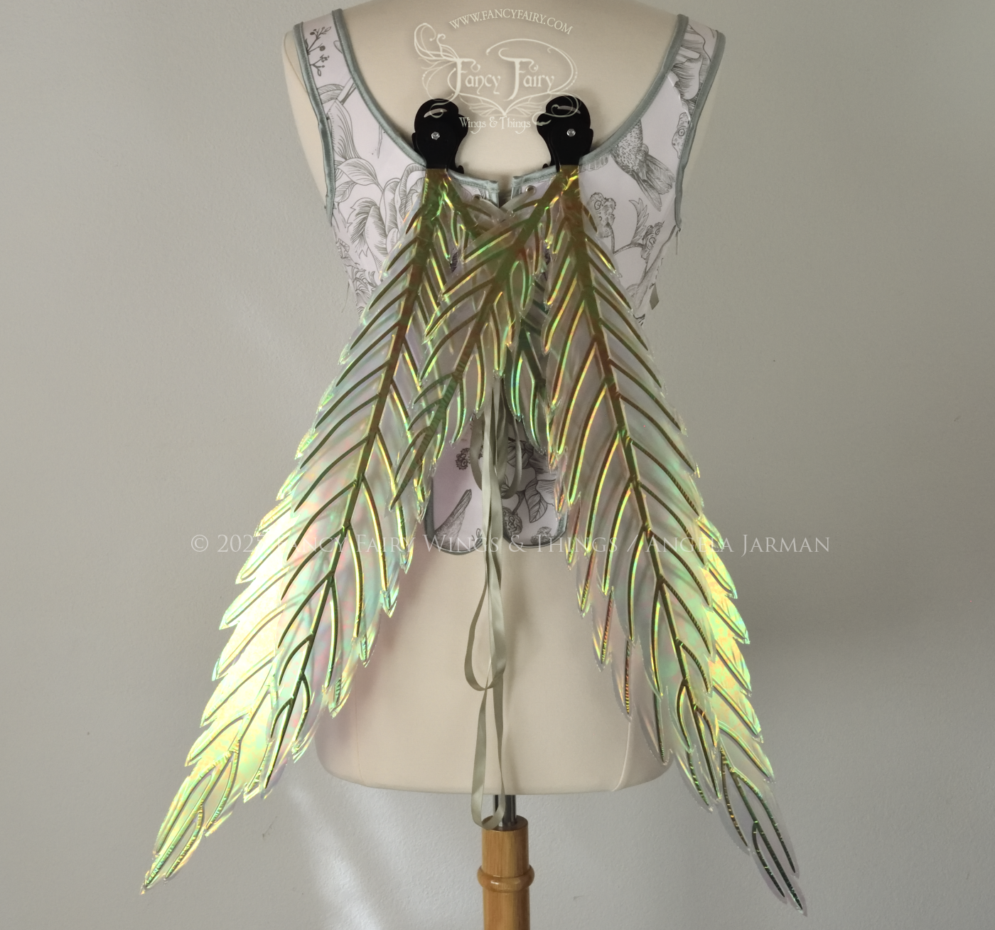 Green iridescent fairy wings styled after hemp leaves with black veins, worn on a dress form, back view, in resting position