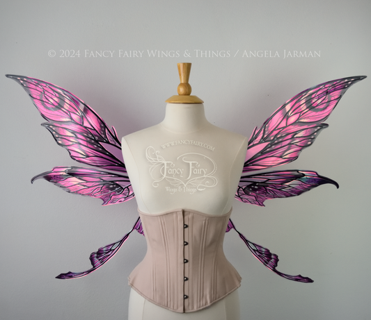 Front view of pointy tipped pink & black iridescent wings in with black detailed veins, worn on a dressform