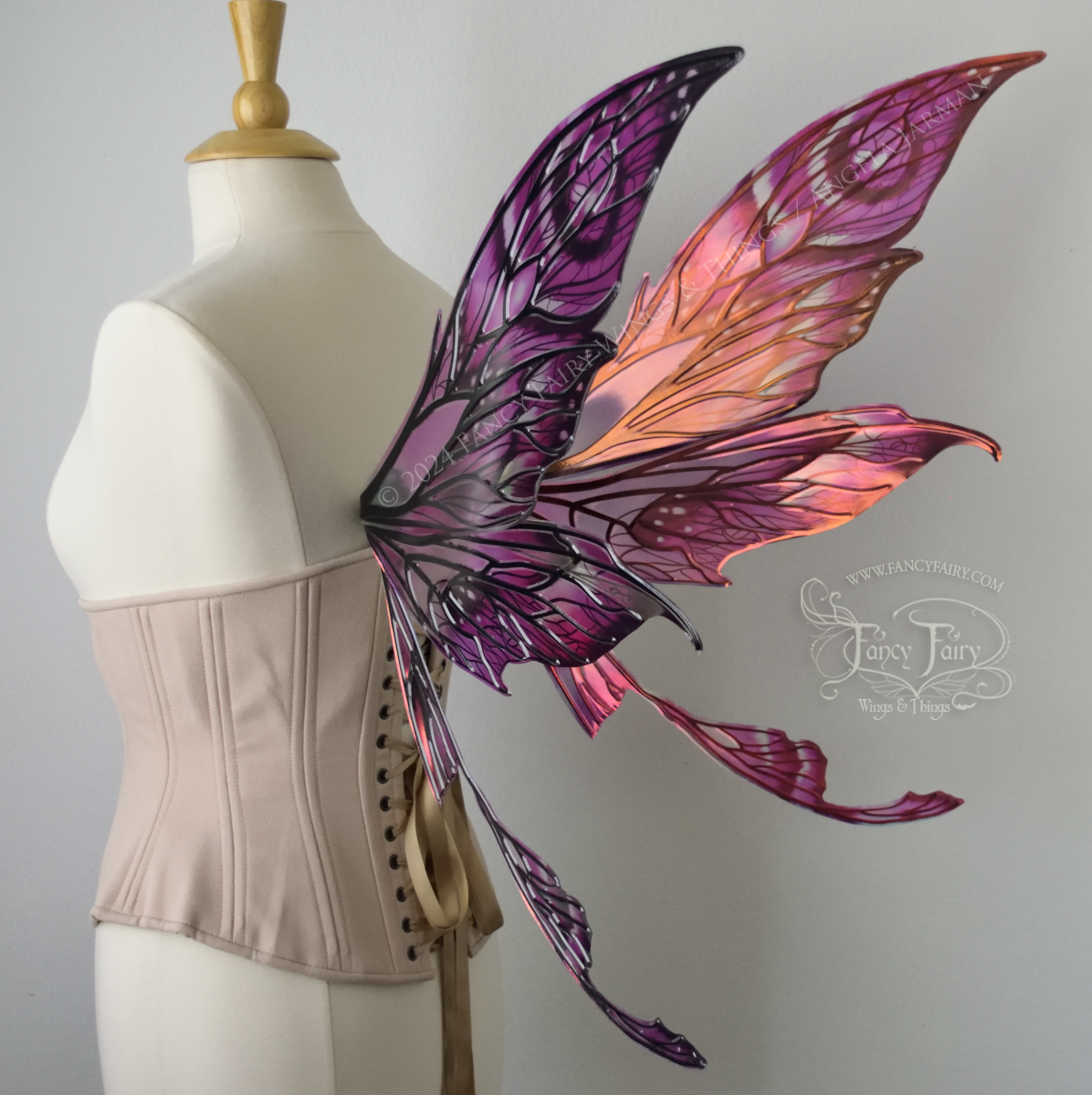 Back 3/4 view of pointy tipped pink & black iridescent wings in with black detailed veins, worn on a dressform