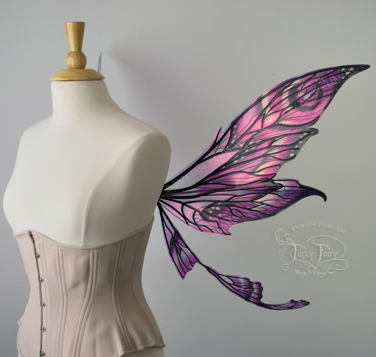 Right side view of pointy tipped pink & black iridescent wings in with black detailed veins, worn on a dressform