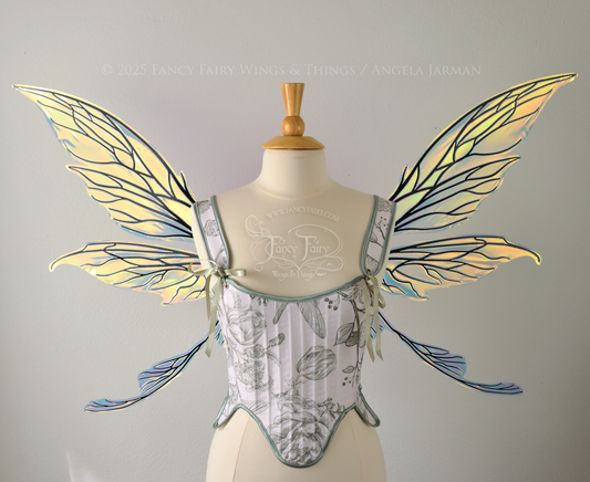 Transparent & iridescent fairy wings reflecting yellow, orange & green with black veins, upper and lower panels are elongated with pointed tips, & curved up ‘tail’ on bottom, worn on a dress form, front view