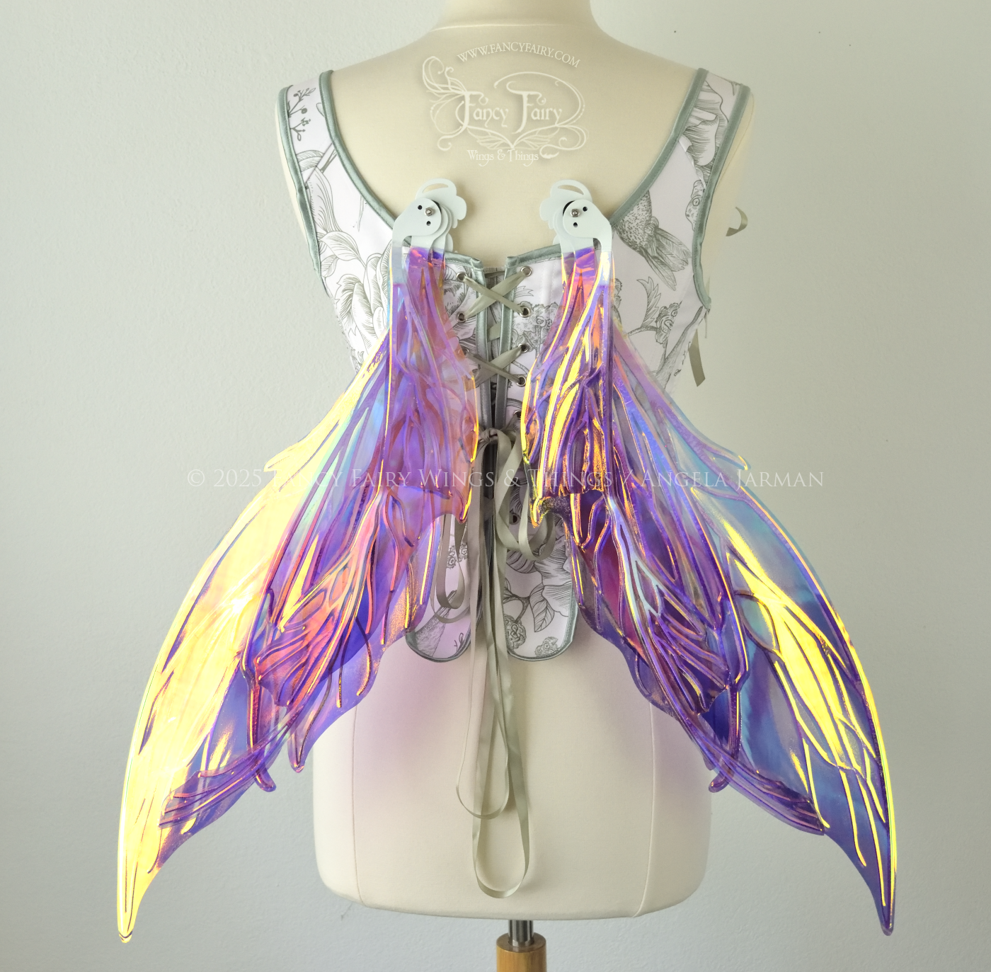 Large painted iridescent fairy wings in berry colors with white veins. Upper panels are elongated with pointed tips, curved ‘tail’, worn on a dress form, back view, in resting position