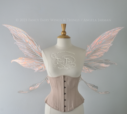 Front view of a dress form wearing an underbust corset and large Rose Gold iridescent fairy wings with tails & lots of detailed white veins.