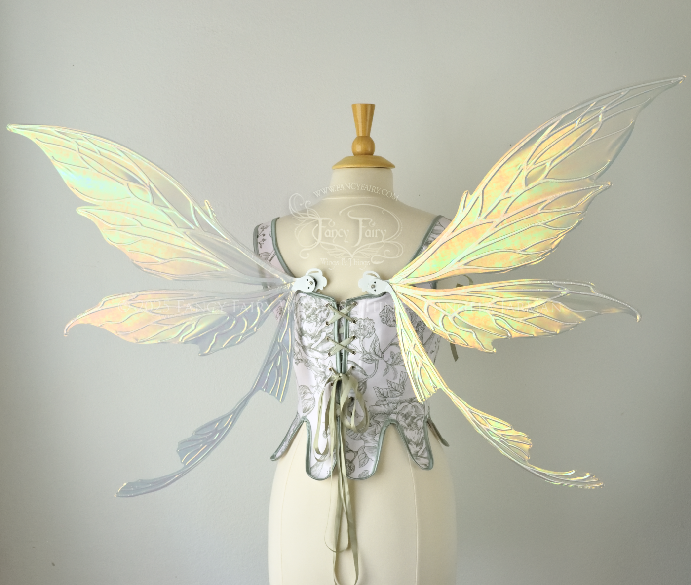 Large iridescent green fairy wings with white veins. Upper panels are elongated with pointed tips, curved ‘tail’, worn on a dress form, back view