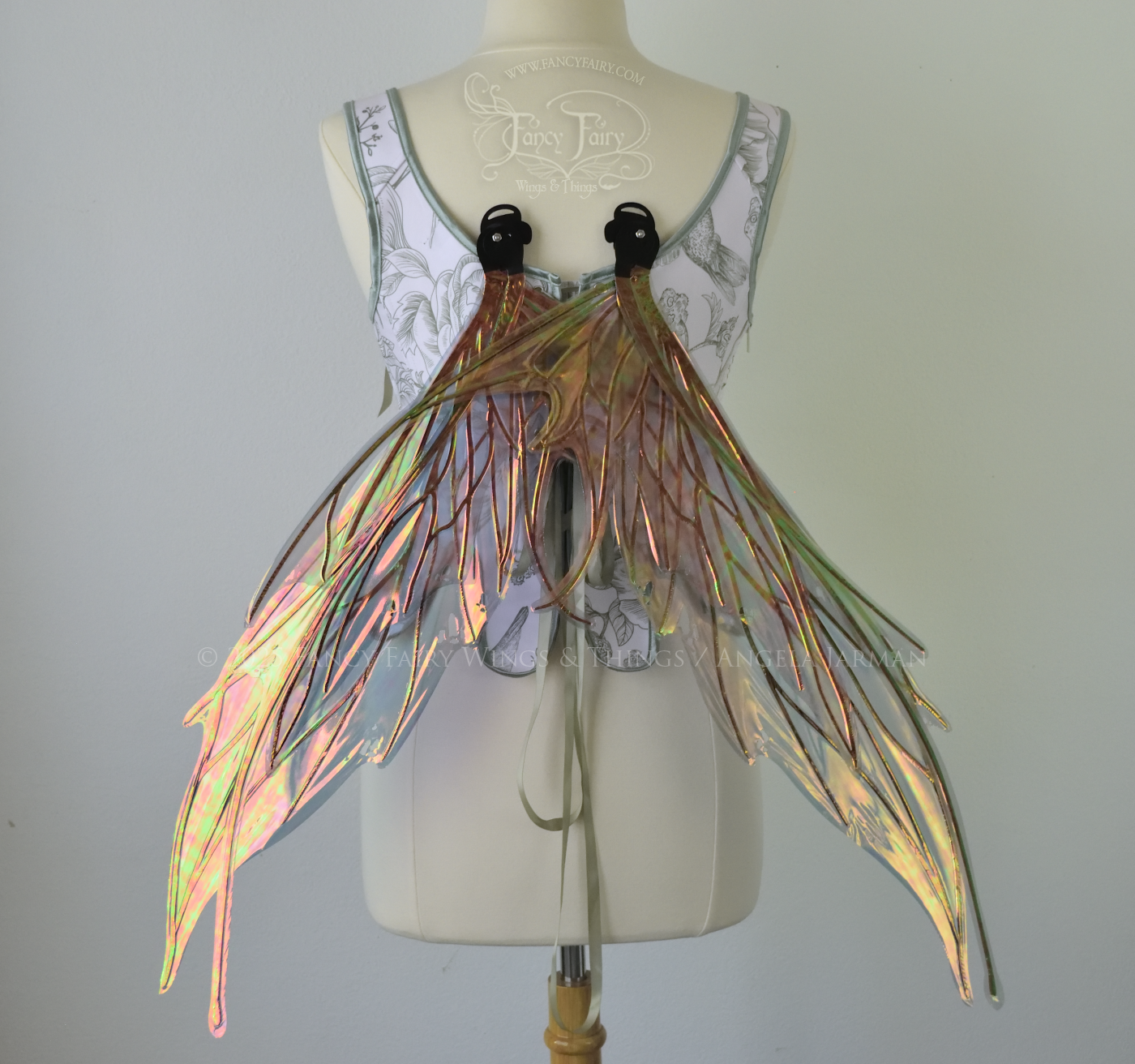 Large orange / green iridescent fairy wings featuring antennae along the top and a spikey profile, worn on a dress form, back view, resting position