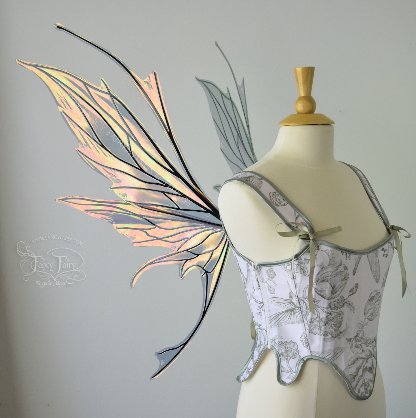 Large orange / green iridescent fairy wings featuring antennae along the top and a spikey profile, worn on a dress form, left side