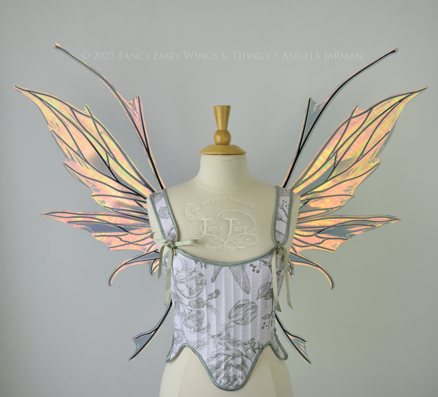 Large orange / green iridescent fairy wings featuring antennae along the top and a spikey profile, worn on a dress form, front view