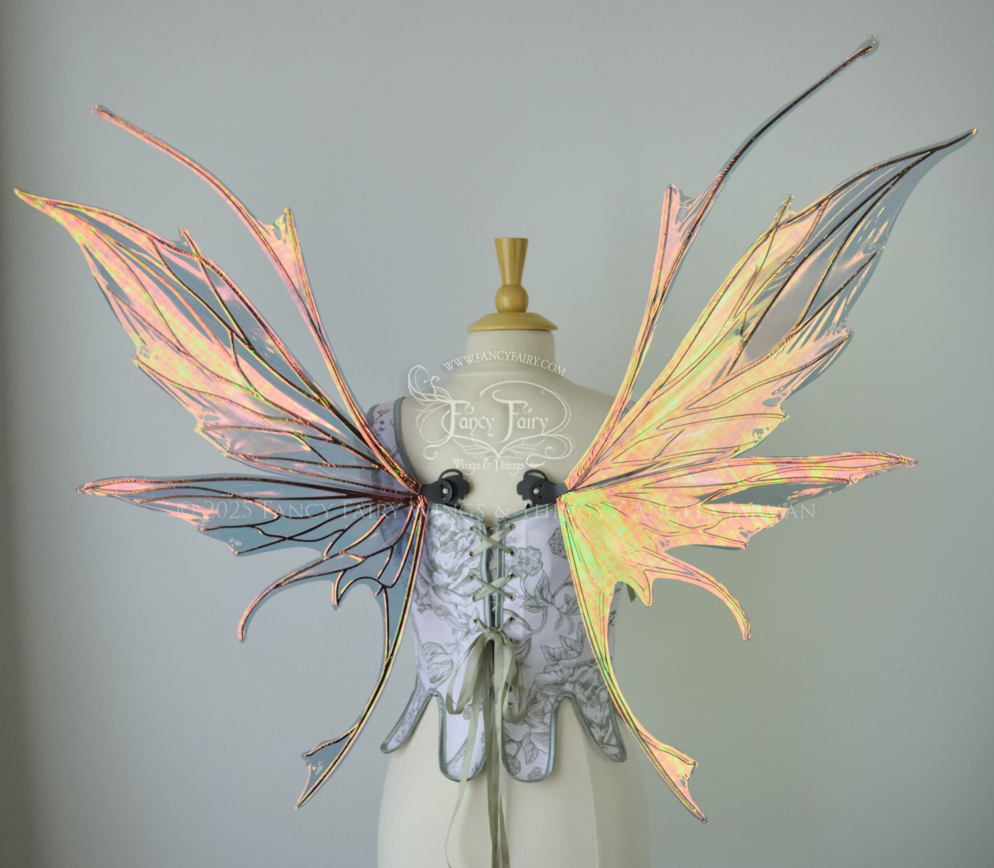 Large orange / green iridescent fairy wings featuring antennae along the top and a spikey profile, worn on a dress form, back view