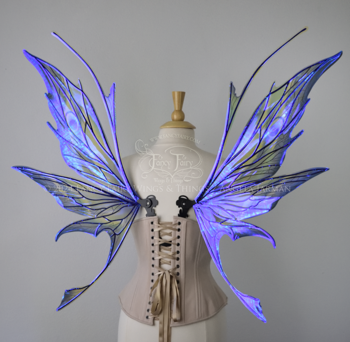 Back view of large spikey blue painted iridescent fairy wings with antennae along the top & black detailed veins, displayed on dress form.