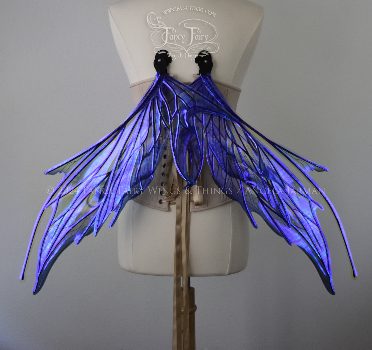 Back view of large spikey blue painted iridescent fairy wings with antennae along the top & black detailed veins, displayed on dress form in resting position.