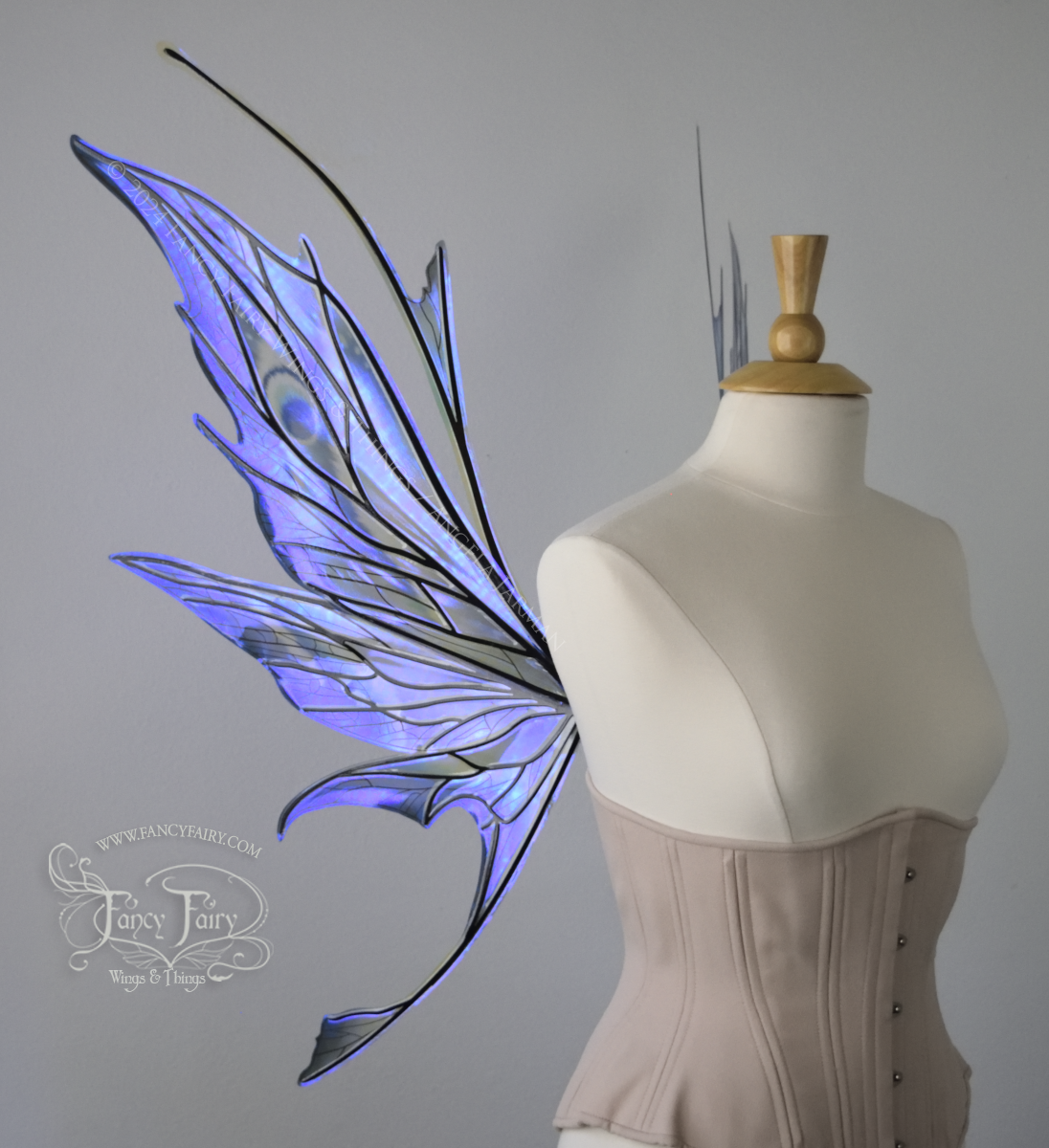 Left side view of large spikey blue painted iridescent fairy wings with antennae along the top & black detailed veins, displayed on dress form.