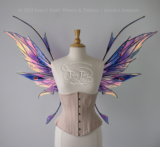 Front view of a dress form wearing an underbust corset & large blue / lavender / red painted iridescent fairy wings with antennae, black veins, spikey shapes