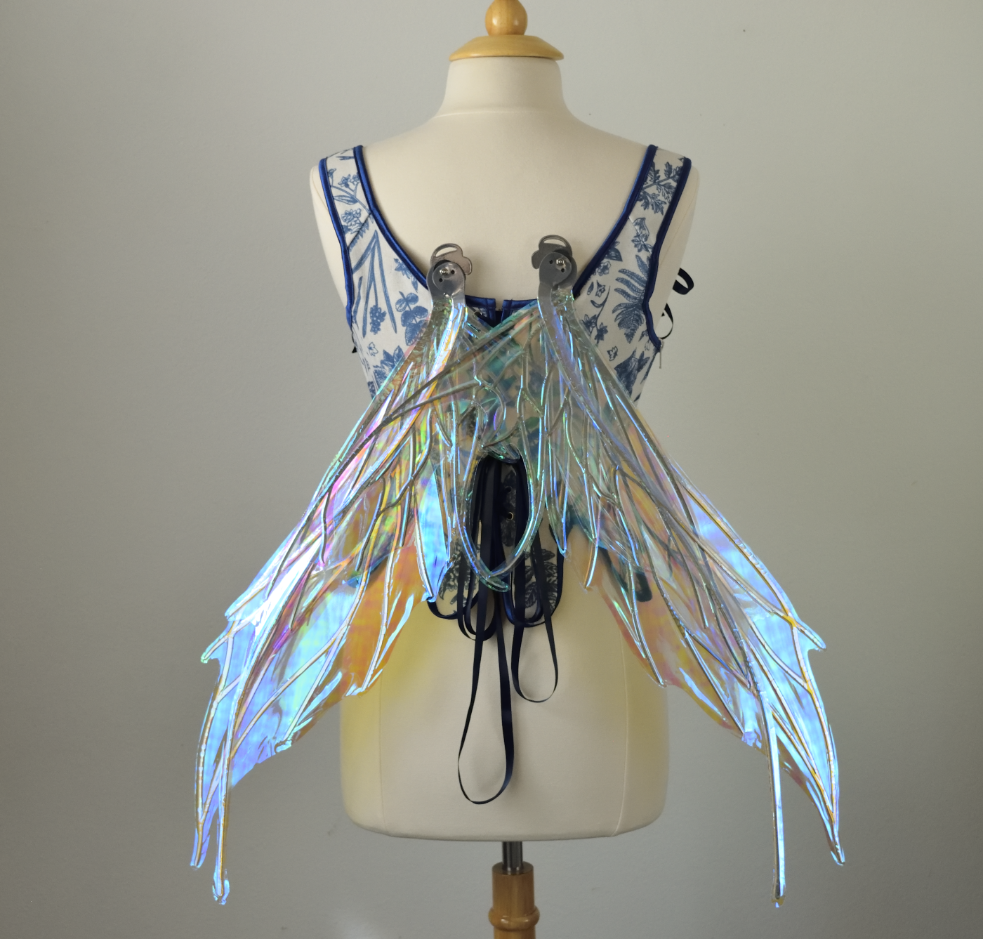Large blue / green iridescent fairy wings with silver veins featuring antennae along the top and a spikey profile, worn on a dress form, back view, in resting position