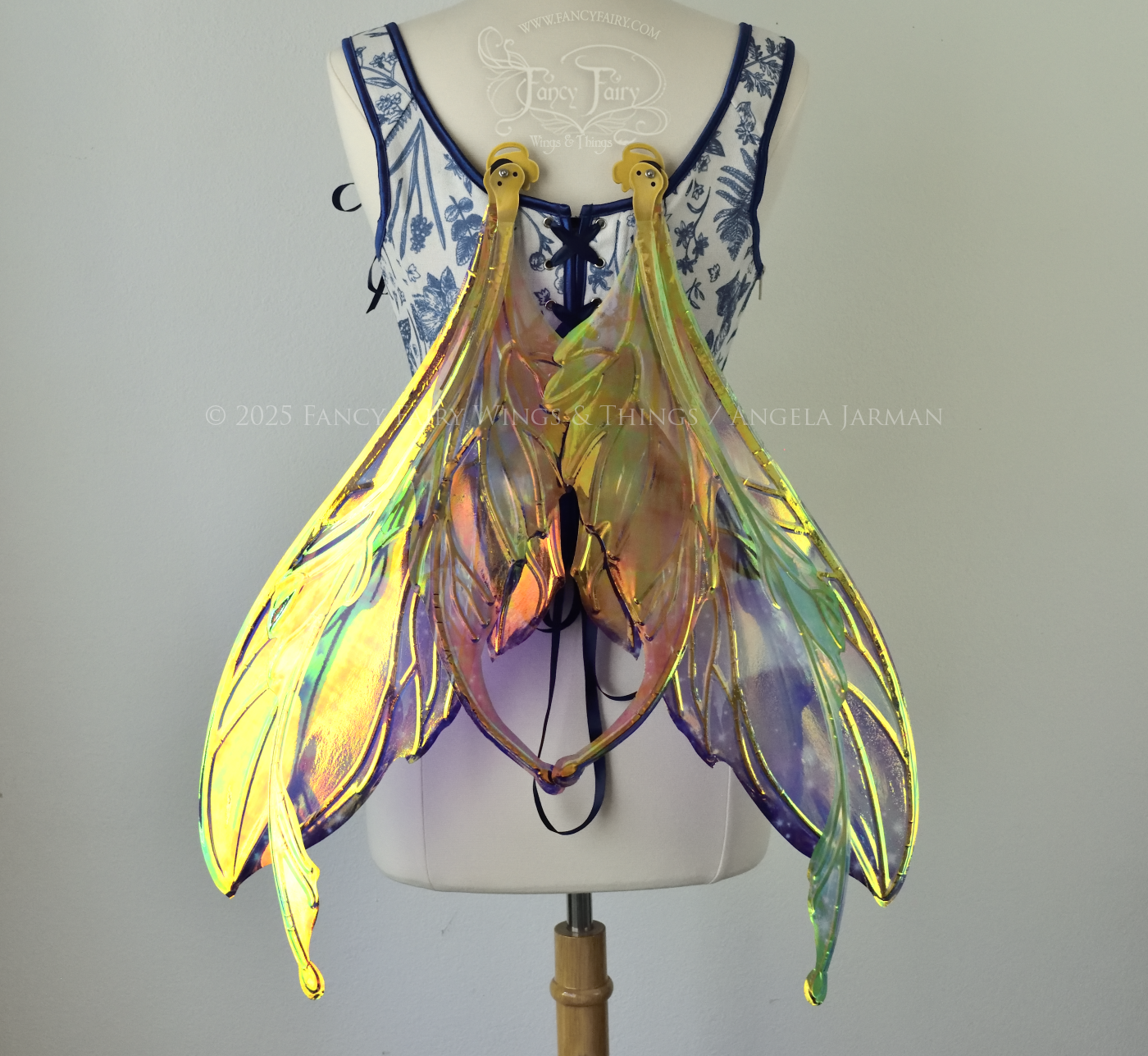 Iridescent fairy wings with a spacey night sky painted on them, with auroras, nebulae and stars, with gold veins & antennae, worn on a dress form, back view, in resting position.