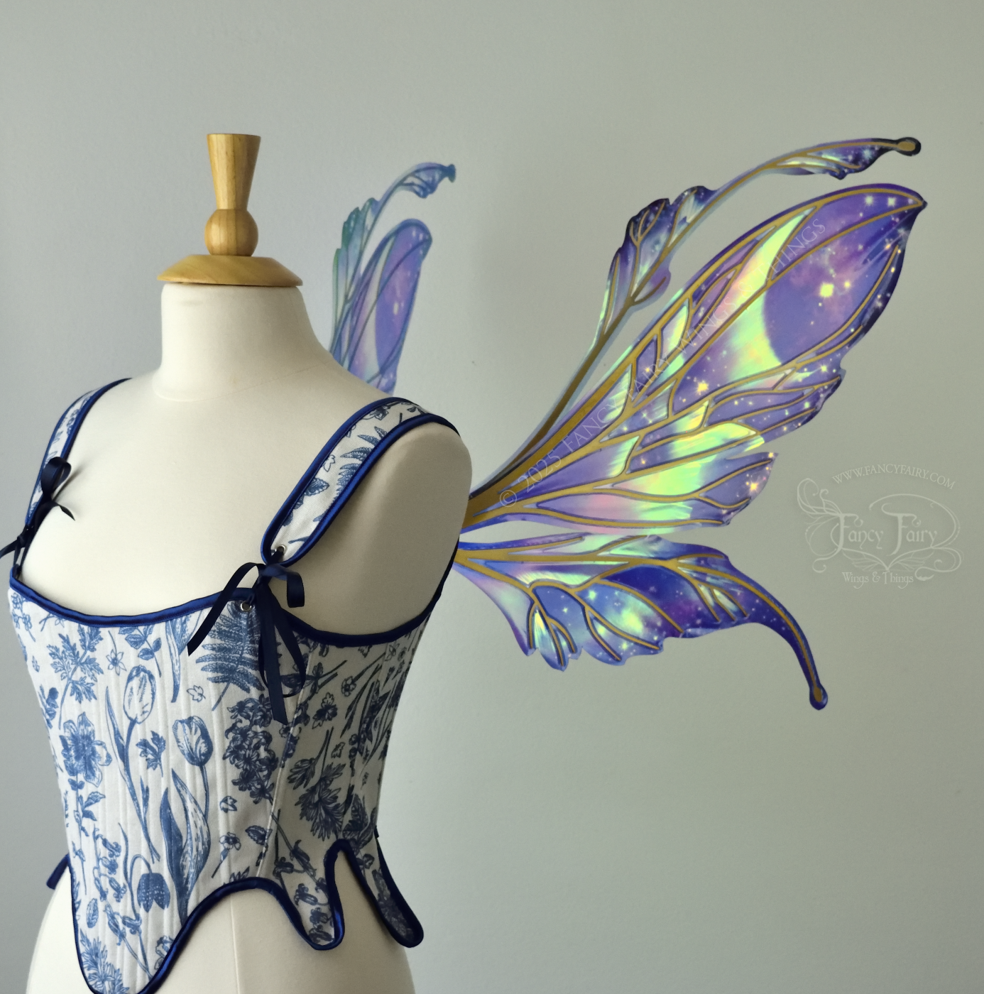 Iridescent fairy wings with a spacey night sky painted on them, with auroras, nebulae and stars, with gold veins & antennae, worn on a dress form, right side view.