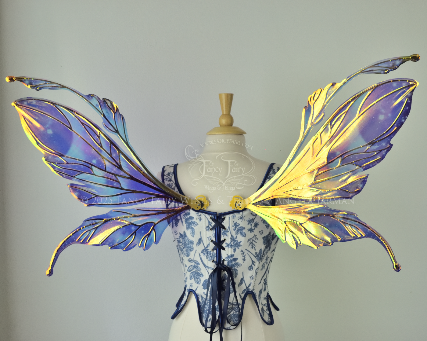 Iridescent fairy wings with a spacey night sky painted on them, with auroras, nebulae and stars, with gold veins & antennae, worn on a dress form, back view.