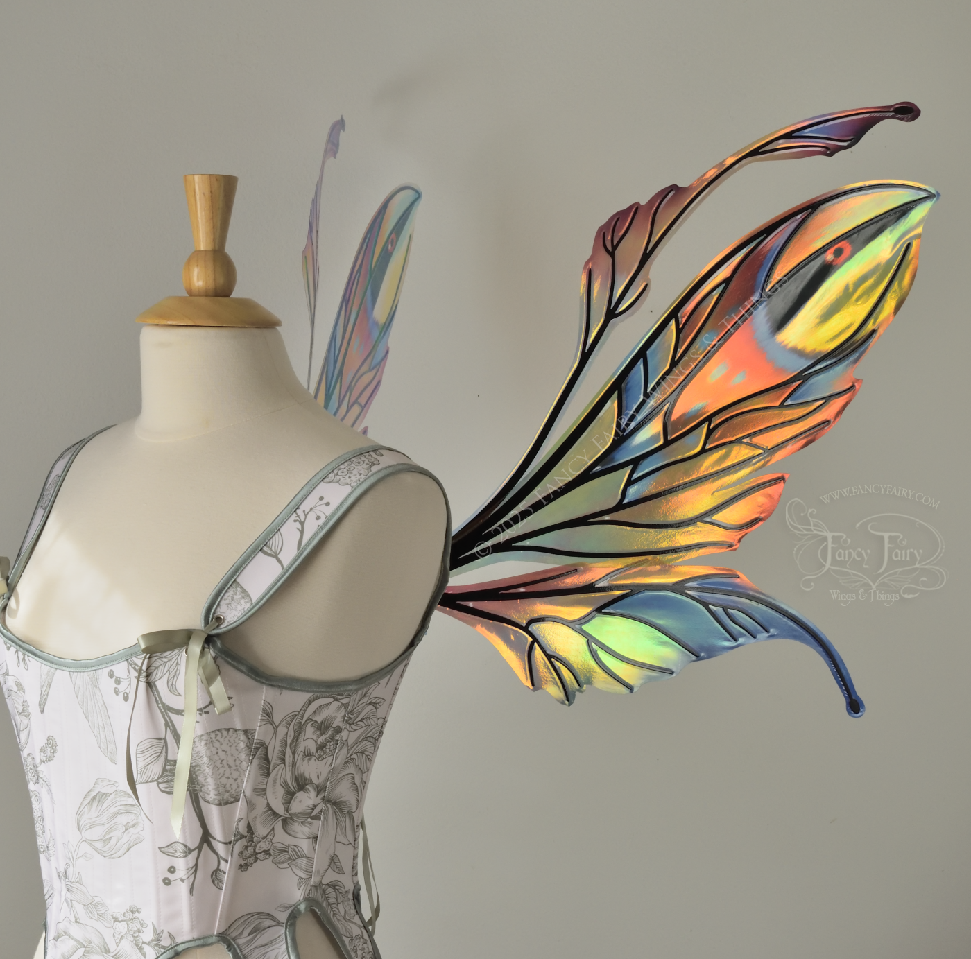 Brightly colored iridescent fairy wings in oranges, yellows, teals and blues with black veins, antennae along the top, worn on a dress form, right side view