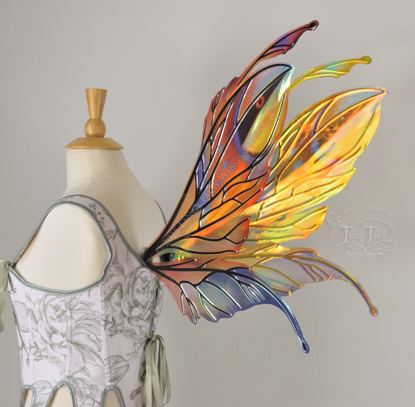Brightly colored iridescent fairy wings in oranges, yellows, teals and blues with black veins, antennae along the top, worn on a dress form, right back 3/4 view