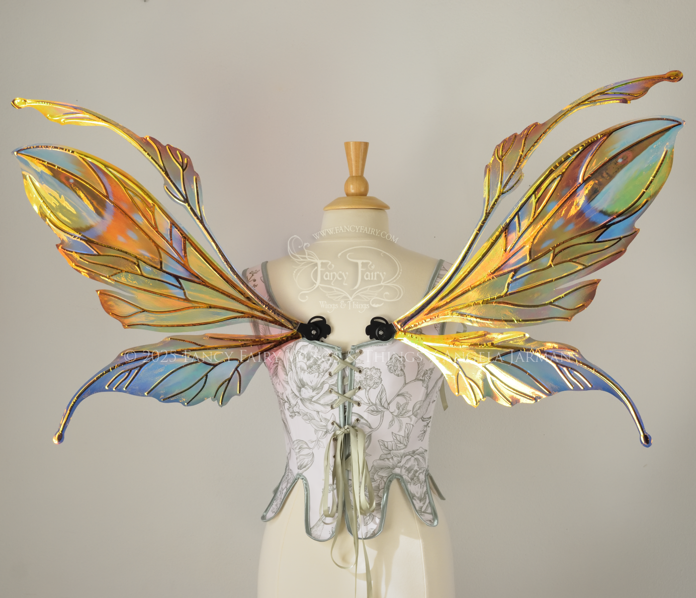Brightly colored iridescent fairy wings in oranges, yellows, teals and blues with black veins, antennae along the top, worn on a dress form. Back view