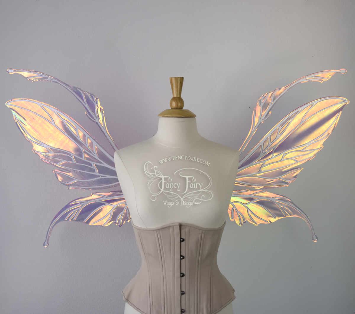 Front view of an ivory dress form wearing an alabaster underbust corset and large fairy wings featuring antennae along the top. The upper panels are elongated with semi-pointed tips, the lower panels are smaller with slender tips that curve downward. They are pink iridescent with a orange & yellow shine and the veins are white. The background is plain white and my logo and copyright notice are visible.