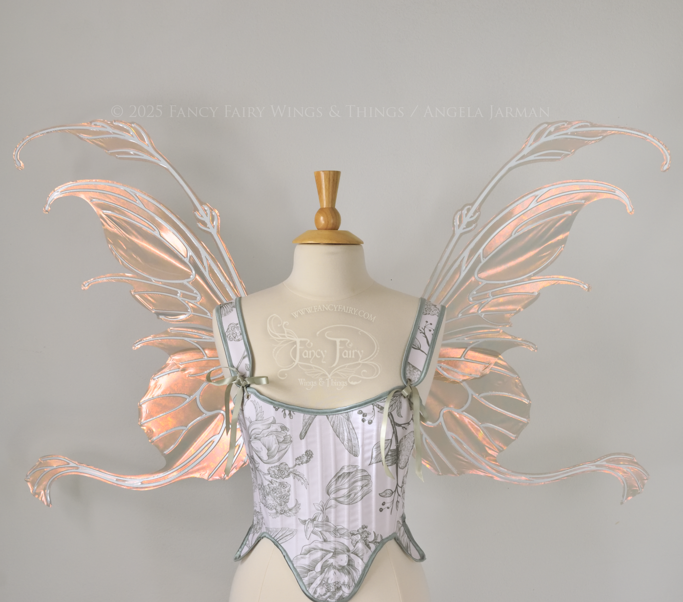 Rose gold iridescent transparent fairy wings with antennae and tails on the bottom panels with white veins, worn on a dress form, front view