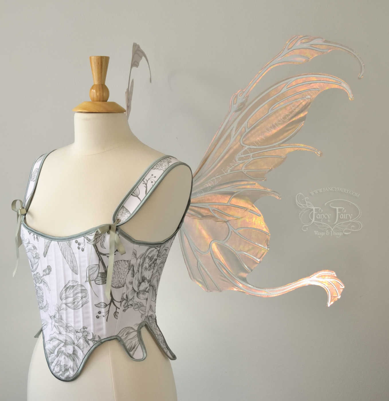 Rose gold iridescent transparent fairy wings with antennae and tails on the bottom panels with white veins, worn on a dress form, right side view
