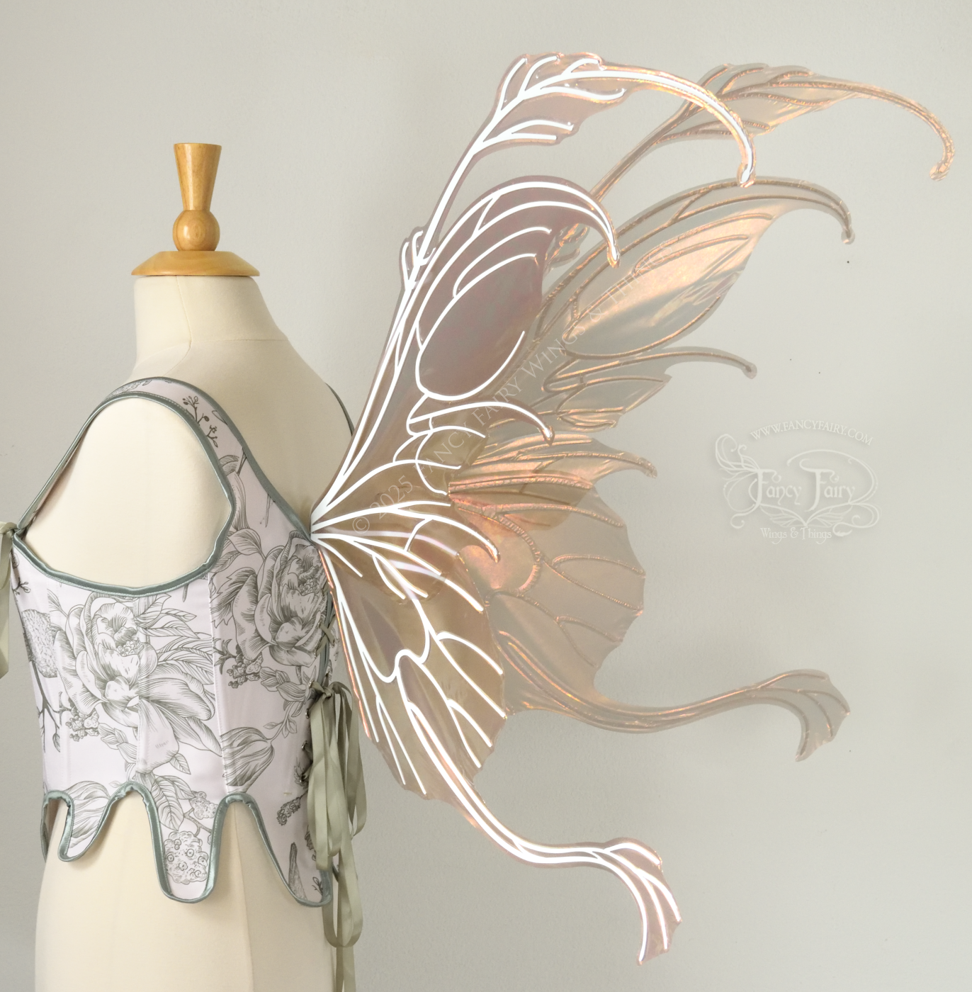 Rose gold iridescent transparent fairy wings with antennae and tails on the bottom panels with white veins, worn on a dress form, back 3/4 view