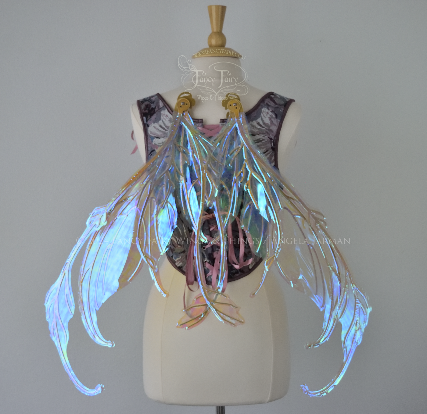 Large blue / green transparent iridescent fairy wings with downward curved tips, antennae & appendages, gold veins, worn on a dress form, back view, in resting position