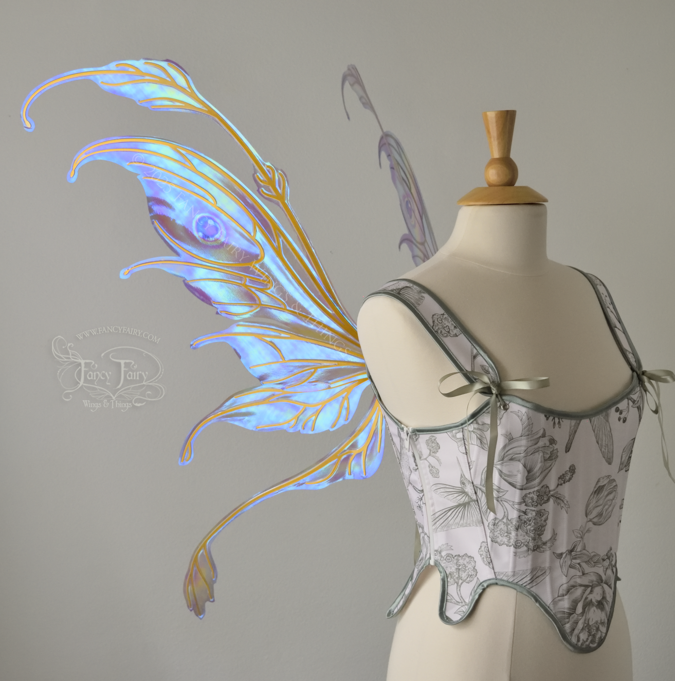 Iridescent pastel rainbow fairy wings with downward curved tips, antennae and appendages, with gold veins, worn on a dress form, left side view
