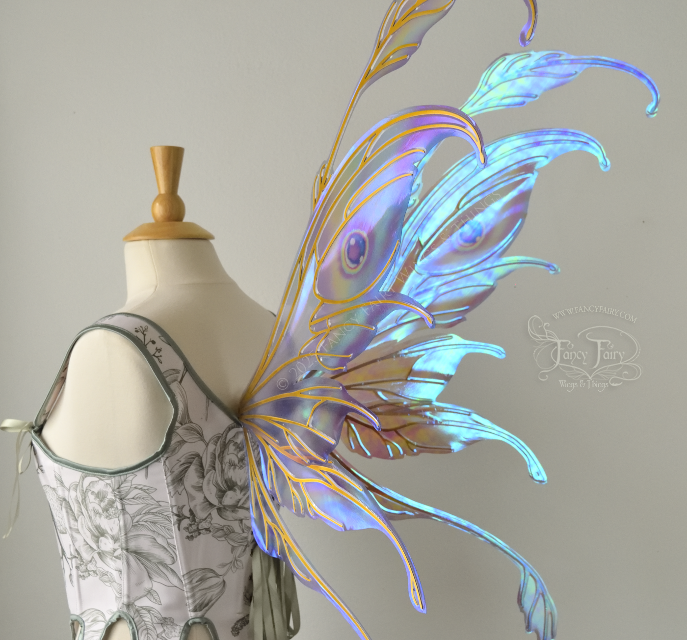 Iridescent pastel rainbow fairy wings with downward curved tips, antennae and appendages, with gold veins, worn on a dress form, back 3/4 view