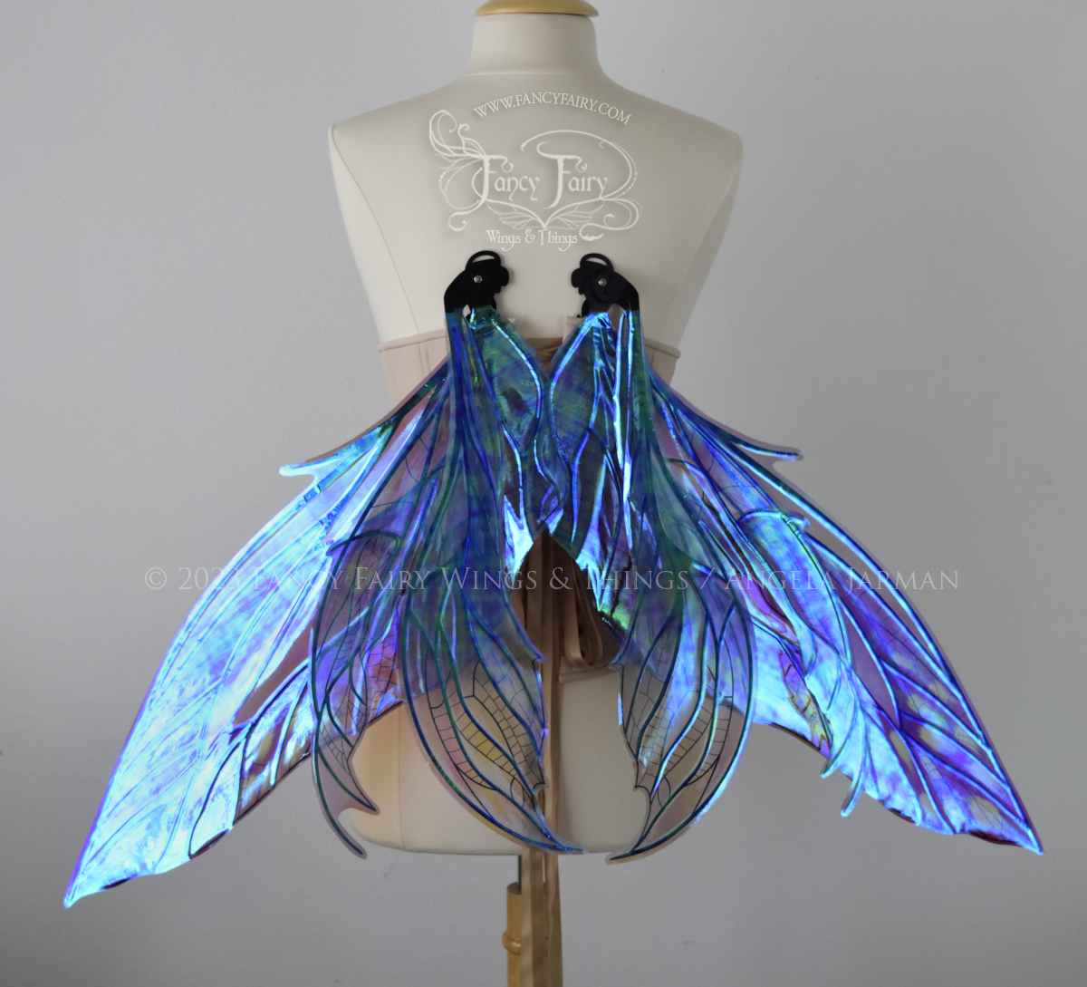 Back view of dress form wearing large plum iridescent fairy wings with green accents. 3 pointed panels each side, detailed black veins, in resting position