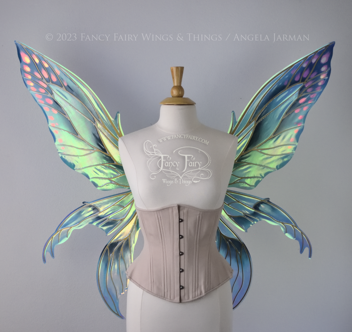 Extra large fairy wings in iridescent green and blue with pink spots near the tips of the upper panels, with gold veins, worn on a dressform