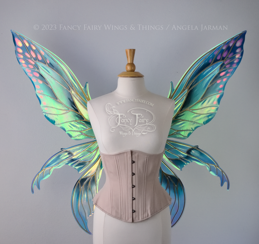 Extra large fairy wings in iridescent green and blue with pink spots near the tips of the upper panels, with gold veins, worn on a dressform