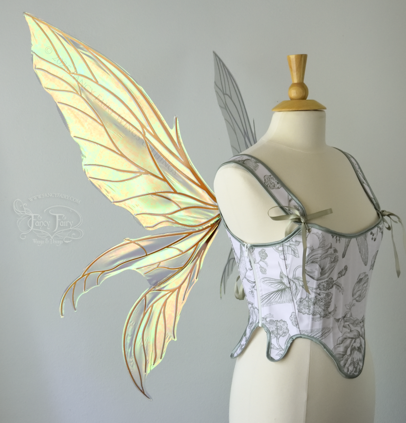 Large transparent iridescent orange/yellow/green dragonfly-like iridescent fairy wings with copper veins have 3 elongated panels on each side, worn on a dress form, left side view