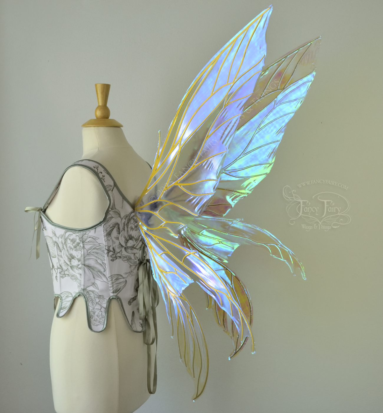 Large transparent blue/green dragonfly-like iridescent fairy wings with gold veins have 3 elongated panels on each side, worn on a dress form, back 3/4 view