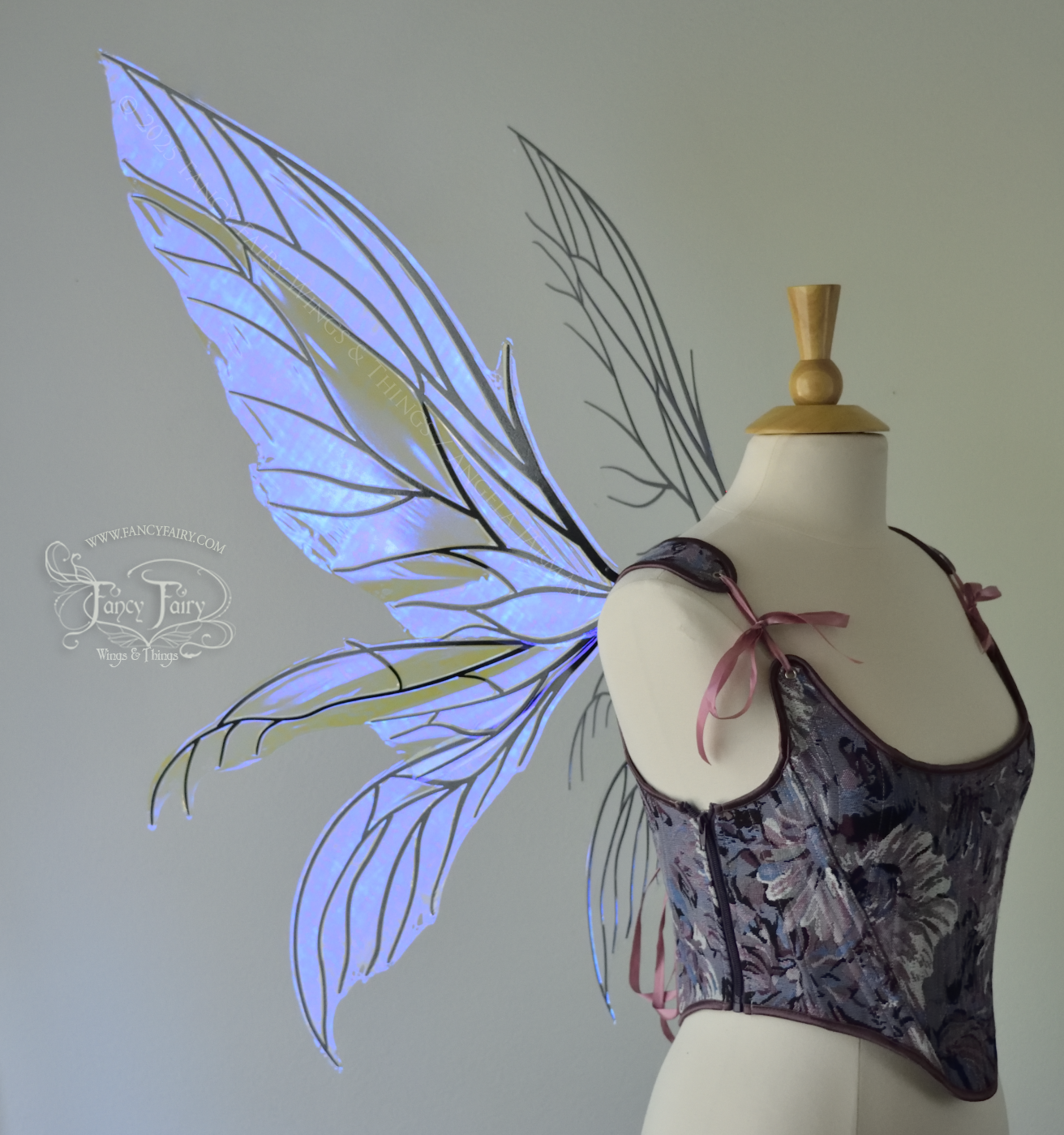 Large violet dragonfly-like iridescent fairy wings with black veins have 3 elongated panels on each side, worn on a dress form, left side view