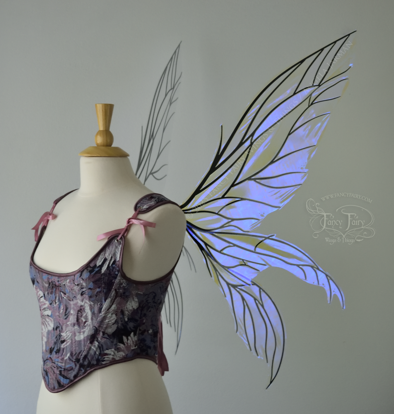 Large violet dragonfly-like iridescent fairy wings with black veins have 3 elongated panels on each side, worn on a dress form, right side view