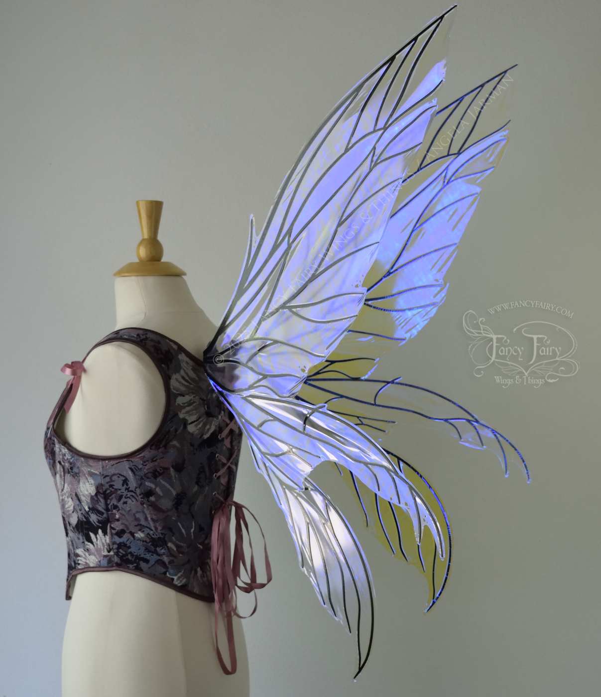Large violet dragonfly-like iridescent fairy wings with black veins have 3 elongated panels on each side, worn on a dress form, back 3/4 view