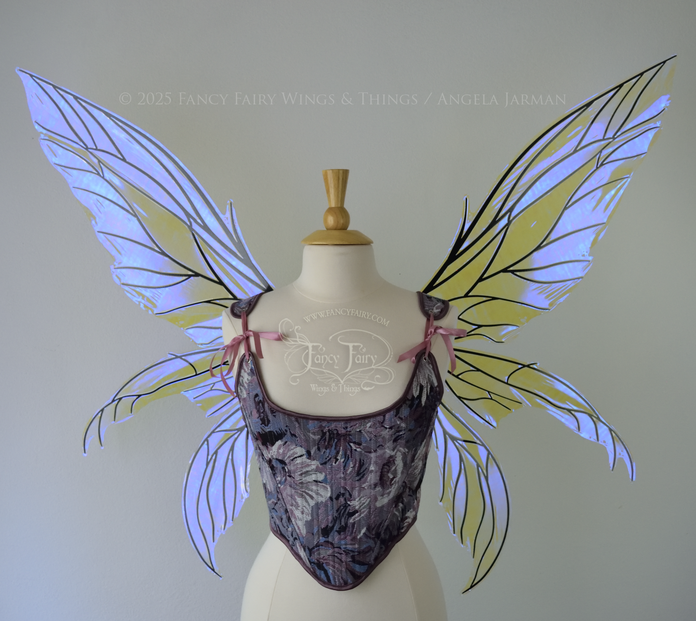 Large violet dragonfly-like iridescent fairy wings with black veins have 3 elongated panels on each side, worn on a dress form, front view