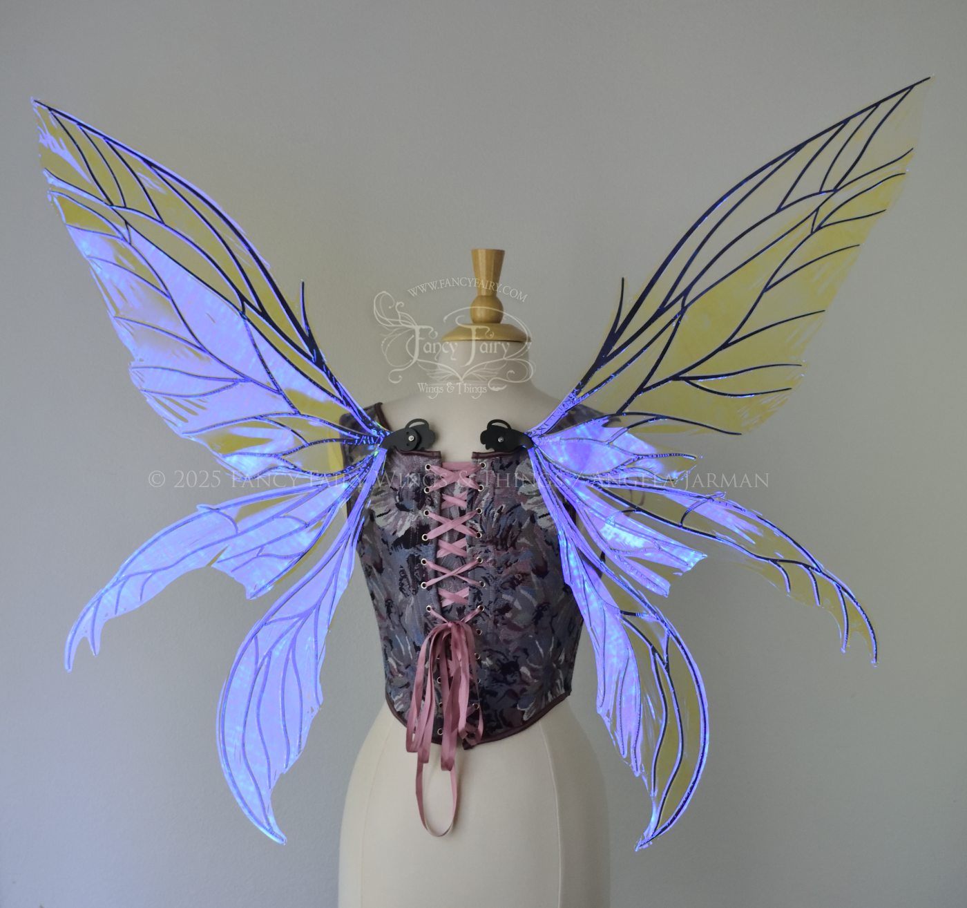 Large violet dragonfly-like iridescent fairy wings with black veins have 3 elongated panels on each side, worn on a dress form, back view