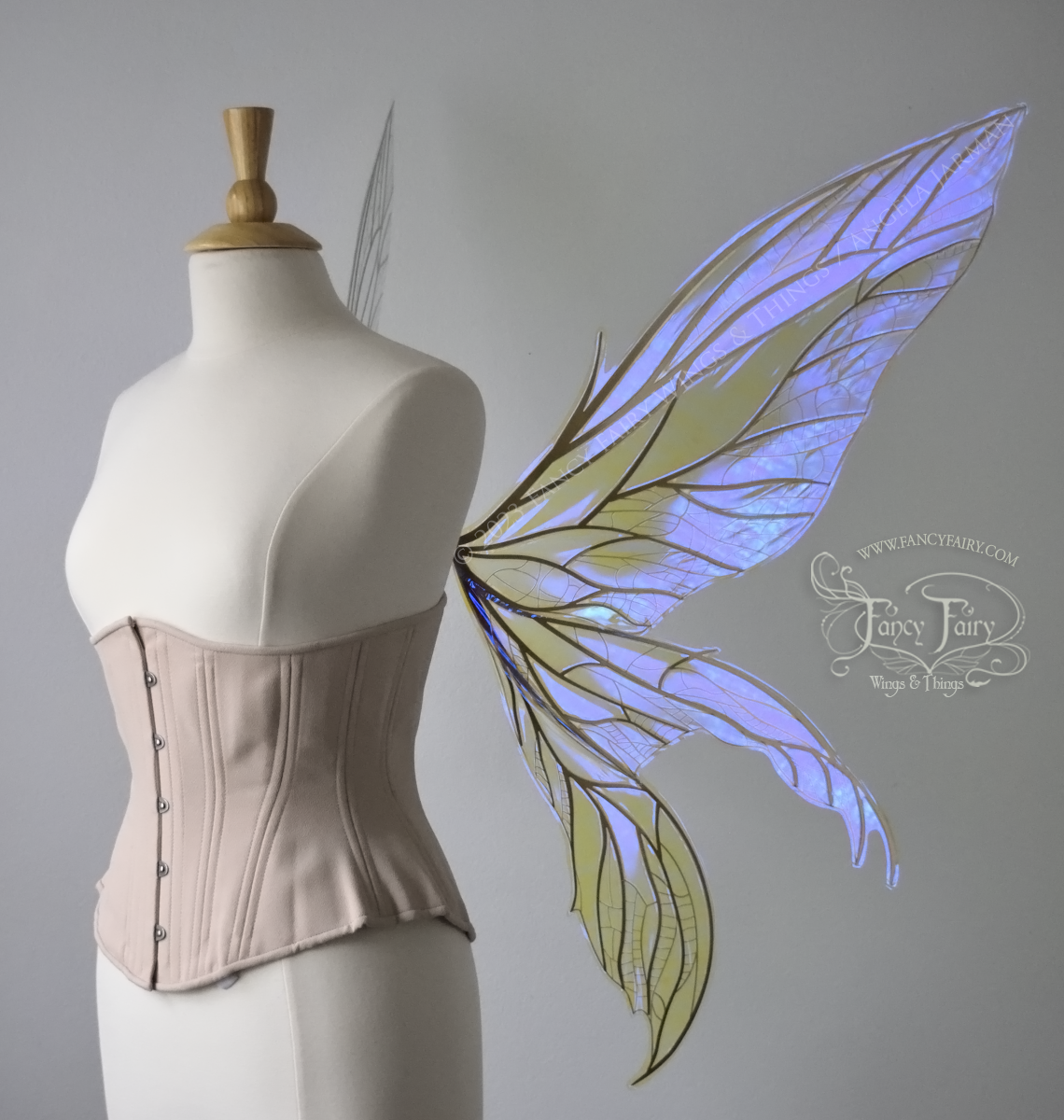 Right side view of an ivory dress form wearing an alabaster underbust corset & large violet iridescent fairy wings. Upper panels are elongated with pointed tips, 2 lower panels curve downward, lots of thin vein detail in gold