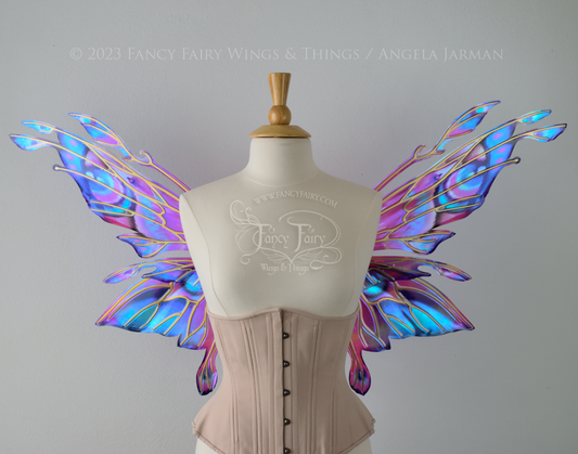 Front view of an ivory dress form wearing an underbust corset & 'Goblin Princess' magenta & blue painted iridescent wings w/ gold veins