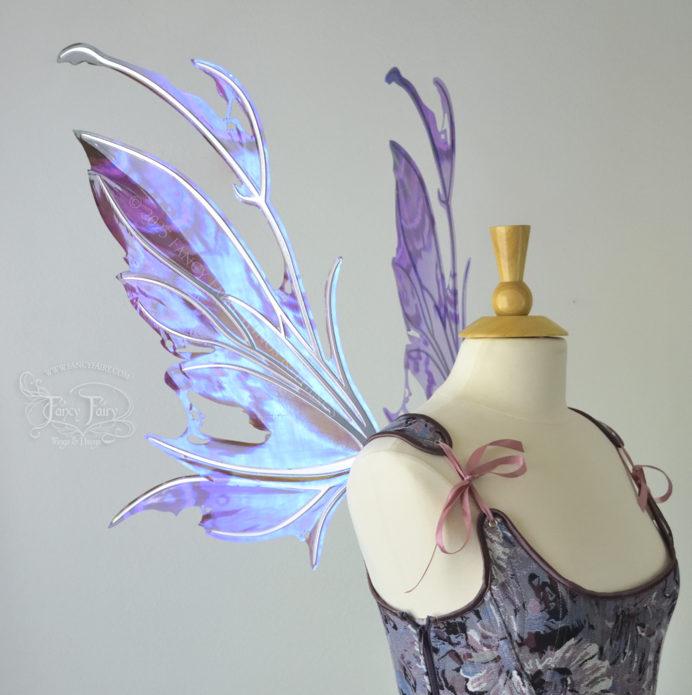 Purple & blue iridescent fairy wings with a spikey profile and antennae, with silver veins, are viewed from the left side, worn on a dress form