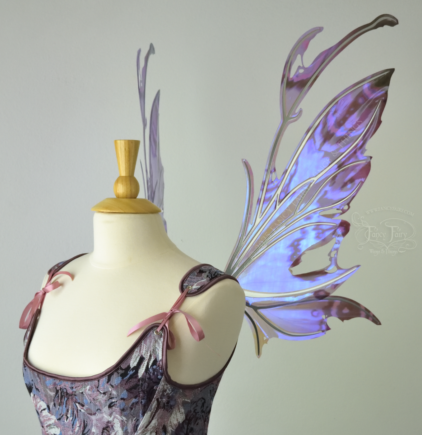 Purple & blue iridescent fairy wings with a spikey profile and antennae, with silver veins, are viewed from the right side, worn on a dress form