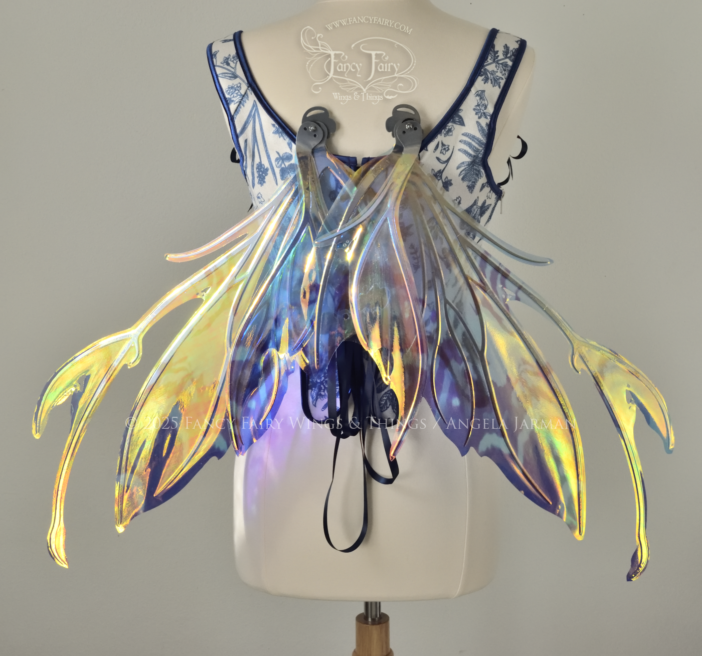 Teal, blue and silver iridescent fairy wings with a spikey profile and antennae are viewed from the back, in resting position, worn on a dress form