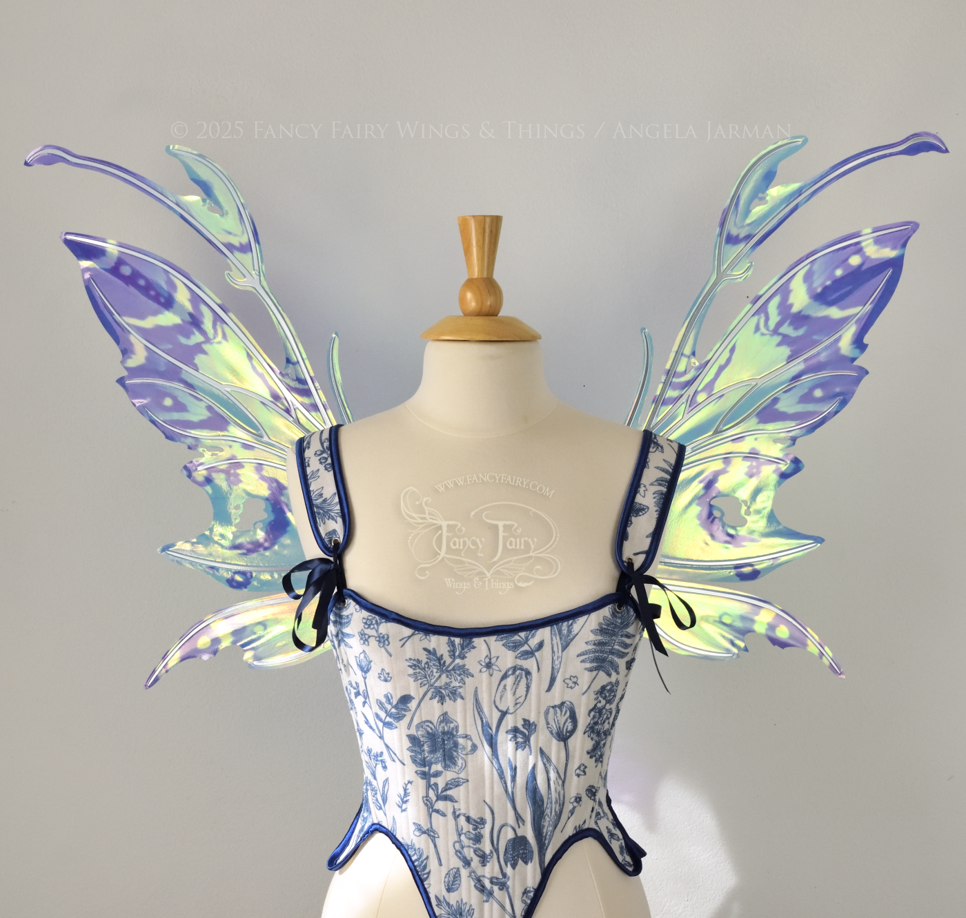 Teal, blue and silver iridescent fairy wings with a spikey profile and antennae are viewed from the front, worn on a dress form