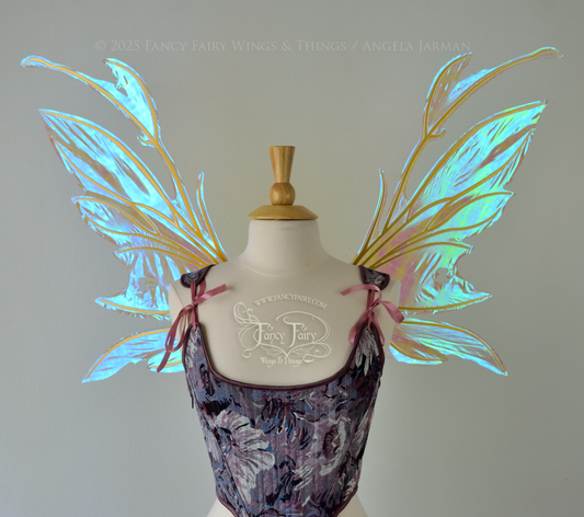 Transparent blue / green iridescent fairy wings with antennae and tattered holes with gold veins, worn on a dress form, front view